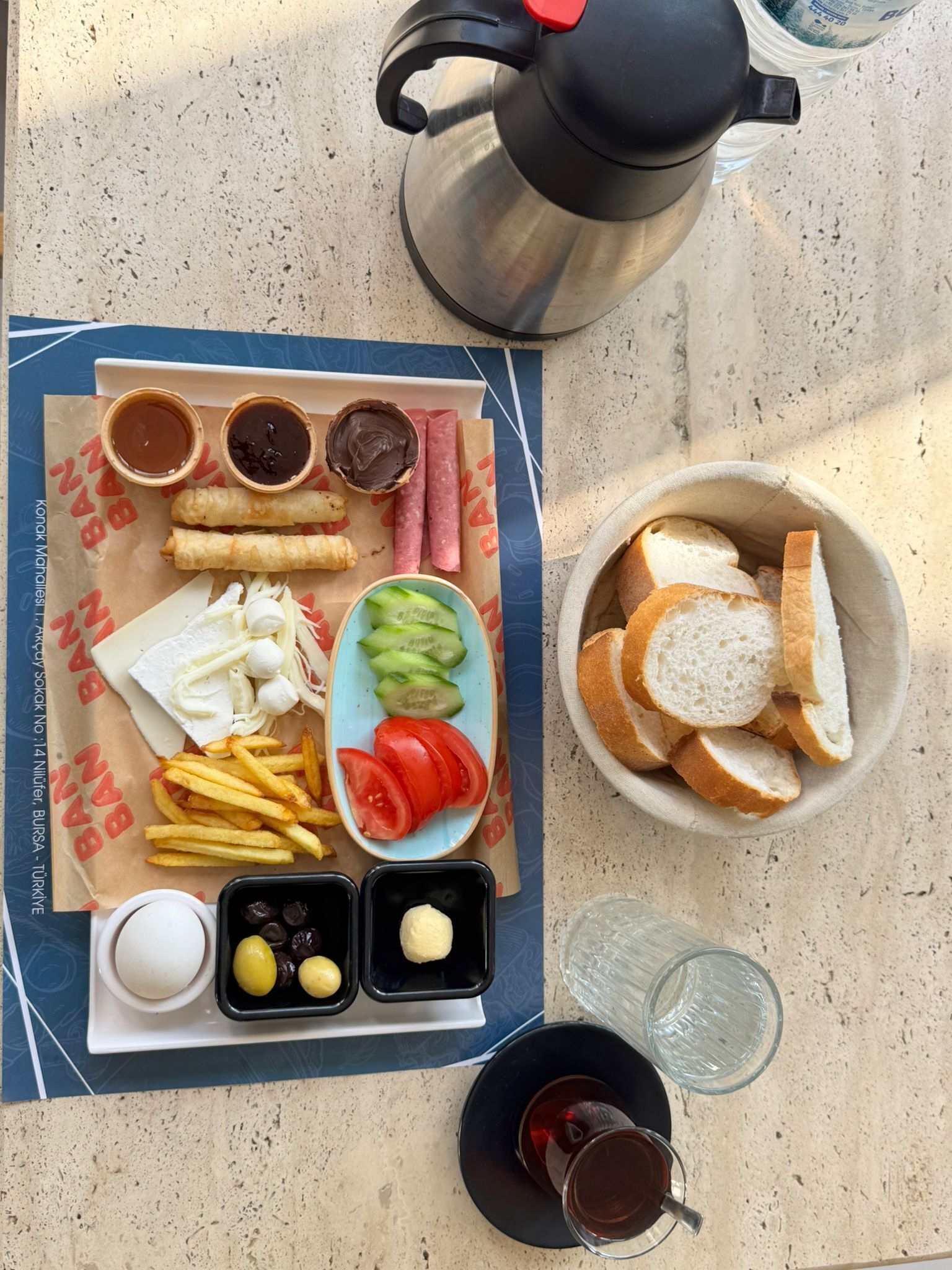 Comida con varios elementos, como pan, papas fritas y verduras, acompañada de bebidas y salsas.