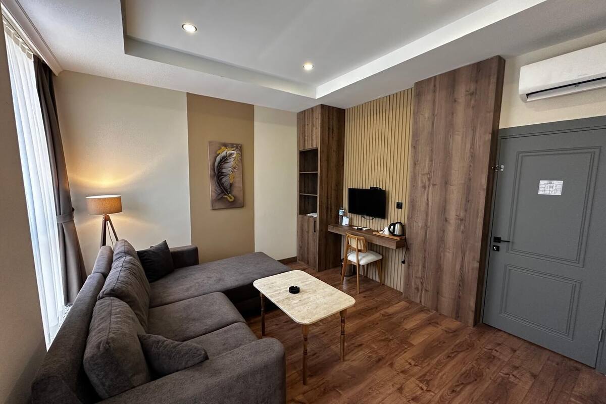 A modern living room with a sofa, a small table, a TV, and a wooden wall panel.