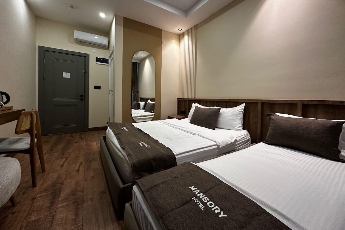 A hotel room with two beds, a desk, and a chair.