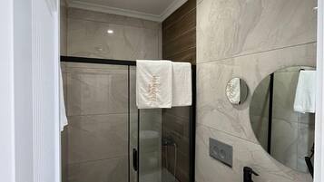 Un baño moderno con ducha de vidrio, inodoro y lavamanos con encimera de madera.