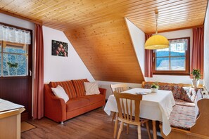 A cozy room with a wooden ceiling, a sofa, a dining table, and a bench.
