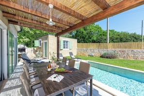Eine Terrasse im Freien mit Holztisch, Stühlen und einem Pool.