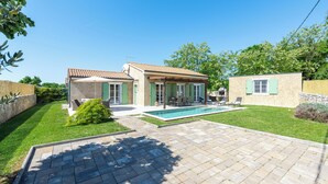 Una casa de dos plantas con piscina, patio y césped cuidado.