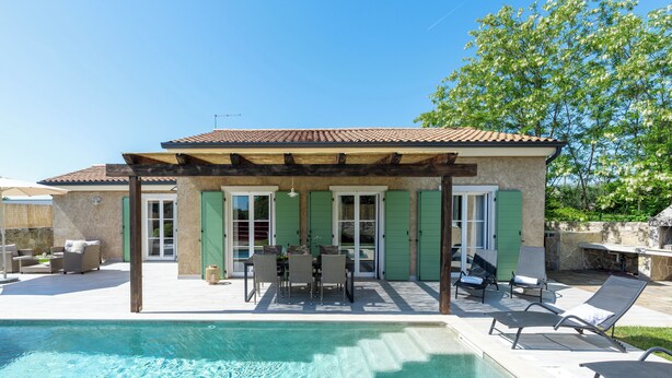 Una zona junto a la piscina con un porche cubierto, mobiliario exterior y vista despejada a la piscina.