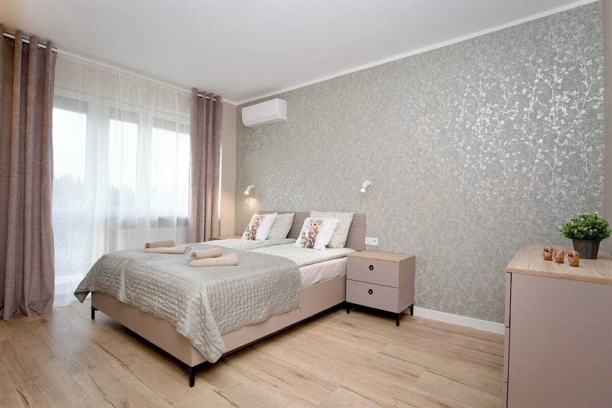 A modern bedroom with a bed, bedside tables, and a dresser.