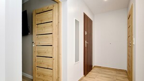 A hallway with wooden doors, a white wall, and a wooden floor. - Łagiewniki Apartments Free Parking (Kraków)