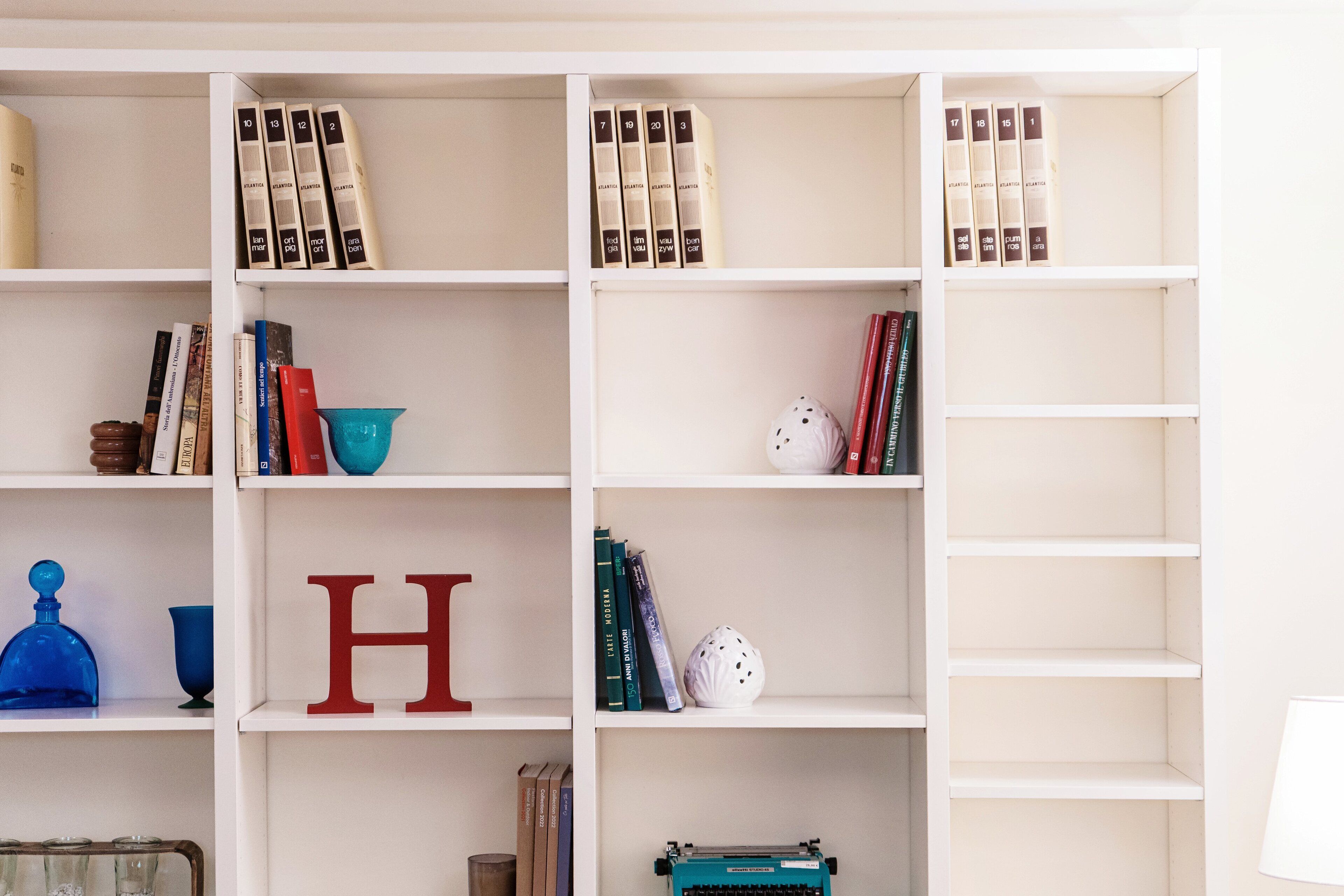 A bookshelf with books, decorative items, and a typewriter.
