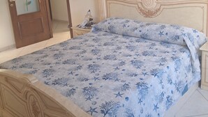 Un dormitorio con cama, cabecera de madera, un cuadro de un paisaje y una puerta con detalle de rosa.