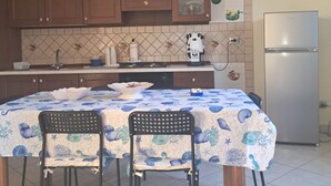 Una cocina con armarios de madera, salpicadero de azulejos, un refrigerador y una mesa de comedor con sillas.