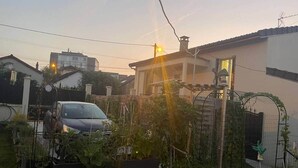 A residential area with a car parked in the driveway, surrounded by potted plants and a garden. - Lena's townhouse (Saint-Denis)