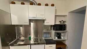 A compact kitchen with white cabinets, a stainless steel sink, and a microwave. - Lena's townhouse (Saint-Denis)