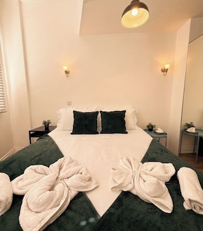 A hotel room with a bed, two bedside tables, a mirror, and a ceiling light.