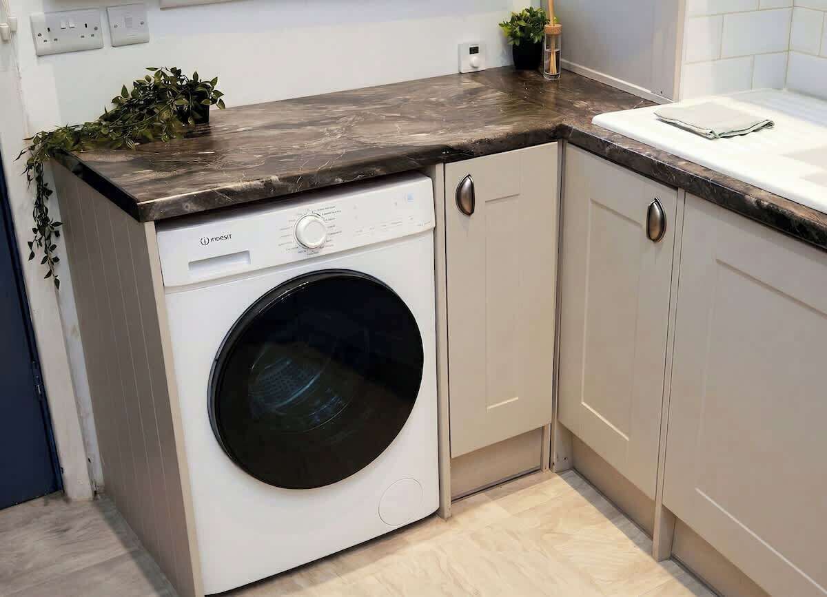 A compact laundry area with a washing machine, cabinets, and a countertop.
