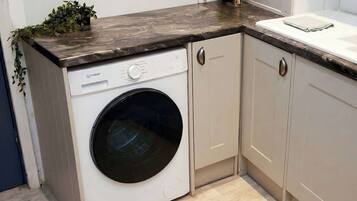 A compact laundry area with a washing machine, cabinets, and a countertop.