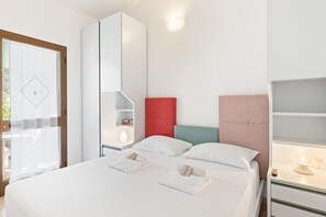 A modern hotel room with a bed, a wardrobe, a nightstand, and a window with a view.