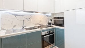 Una cocina moderna con protector contra salpicaduras de mármol, electrodomésticos de acero inoxidable y horno empotrado.