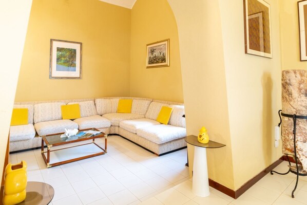 Una sala de estar con un sofá modular, una mesa de centro y una mesita con un objeto decorativo amarillo.