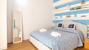 Una camera da letto con un letto, comodini, una cassettiera, uno specchio e una parete con scaffali.