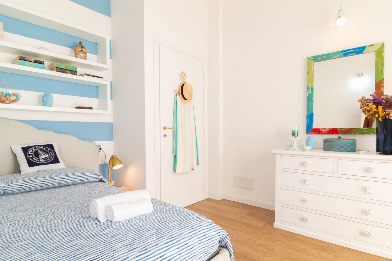 Une chambre à coucher avec un lit, une commode, un miroir et une porte.