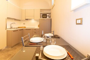 Una cocina compacta equipada con microondas, un lavamanos y una mesa de comedor para dos personas.