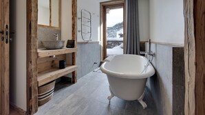 Une salle de bain avec une baignoire sur pieds, un meuble-lavabo en bois, un vasque en pierre et un grand miroir.