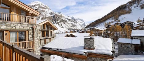 A snow-covered mountain village with stone buildings and wooden balconies.