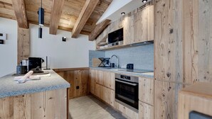 Une cuisine moderne avec des meubles en bois, un four à micro-ondes encastré et un four en acier inoxydable.