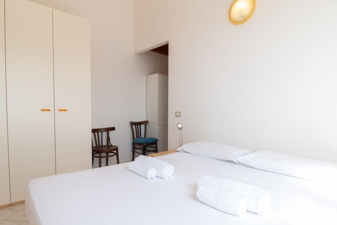Et hotelværelse med en seng, to stole, et skab og et spejl.