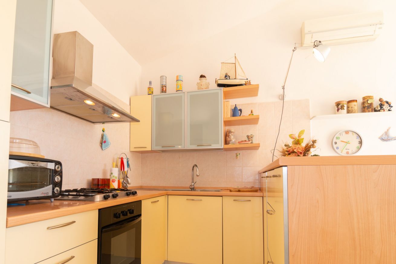Een keukentje met een fornuis, oven, magnetron en een klein spoelbakje.