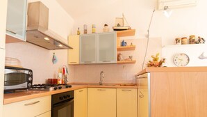 Una cocina compacta con estufa, horno, microondas y un lavamanos pequeño.