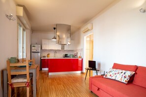 Een compacte woonruimte met kitchenette, een eethoek en een bank.