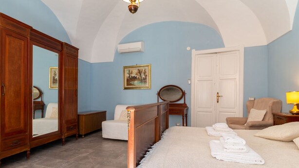 Ein Schlafzimmer mit Bett, Kleiderschrank, Stuhl, Schreibtisch und Spiegel.