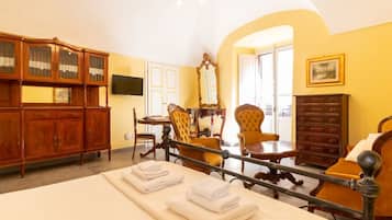 Une chambre d’hôtel comprenant un lit, une armoire en bois, une télévision et un coin repas.