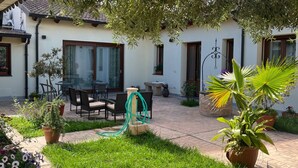 A patio with outdoor furniture, a garden, and a building with windows and doors. - Domo Mea Rooms- Camera 2 (CABRAS)