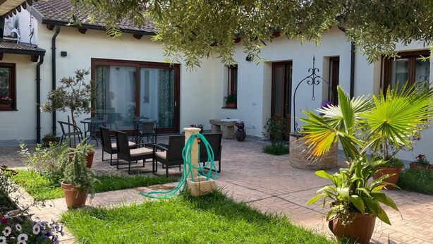 A patio with outdoor furniture, a garden, and a building with windows and doors. - Domo Mea Rooms- Camera 3 (CABRAS)