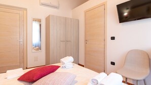 A hotel room with a bed, a TV, a chair, and two wardrobes. - Domo Mea Rooms- Camera 3 (CABRAS)
