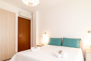 Ein Hotelzimmer mit Bett, Holzschrank, Nachttisch und Wandlampe.