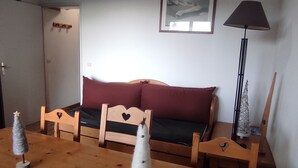 A cozy room with a wooden sofa, a small table with two Christmas trees, and a lamp. - Apartment 5 Pers. with Pool in Super-Besse (Besse-et-Saint-Anastaise-Super Besse)