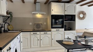 Une cuisine moderne avec des meubles blancs, un îlot central et un coin repas comprenant une table et des chaises.