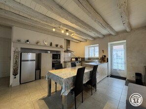 A kitchen with a dining table, chairs, a refrigerator, oven, microwave, and a window.