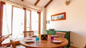 A dining area with a round wooden table, chairs, and a green cabinet. - S'Imbucada Home-Mare e Relax (SAN VERO MILIS)