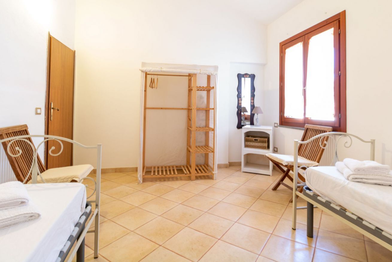Een slaapkamer met twee bedden, een houten garderobe, een spiegel en een raam.