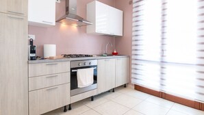 Une cuisine moderne équipée d’une cuisinière à gaz, d’un four et de meubles blancs.