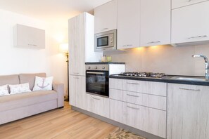 Una cocina moderna con horno integrado, microondas y estufa a gas.