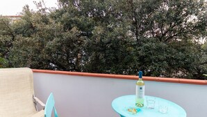 Un balcon avec une table, une chaise et une bouteille de vin.