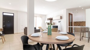 Un espace repas moderne avec une table ronde, des chaises et un vase de fleurs.