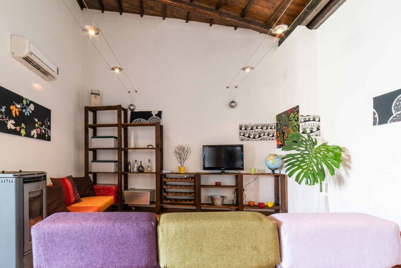 Een gezellige woonkamer met een televisie, houten schappen en een grote plant.