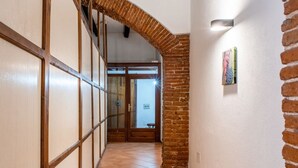 A hallway with a tiled floor, a brick column, and a wooden door frame. - In Barberia- Cozy Corner (Milis)