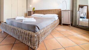 A bedroom with a wicker bed, a nightstand, a mirror, and a wardrobe. - In Barberia- Cozy Corner (Milis)