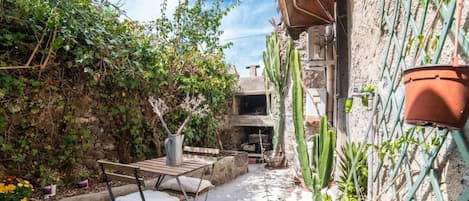 A courtyard with a table and chairs, a potted plant, and a cactus.